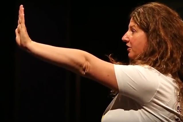 Singer songwriter Sarah Mandie, in white t-shirt, raises her left hand during rehearsals for That Girl Wodonga