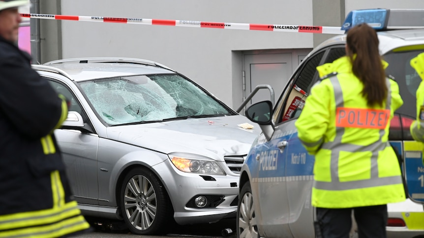 Police stand next to the scene of a car accident.