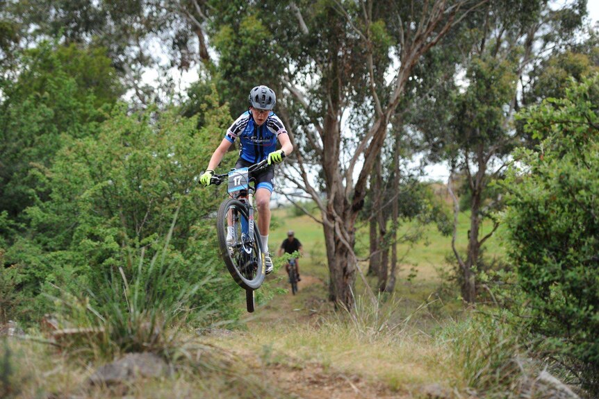 A competitor in a Tasmanian mountain bike race becomes airborne