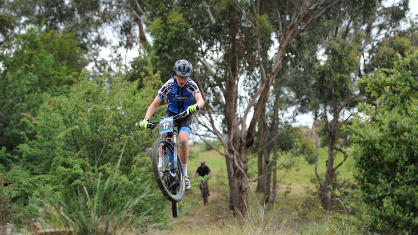 A competitor in a Tasmanian mountain bike race becomes airborne
