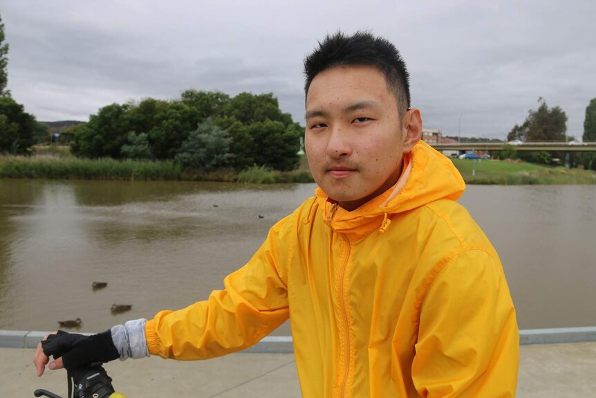 A teenage boy sitting on a bike.