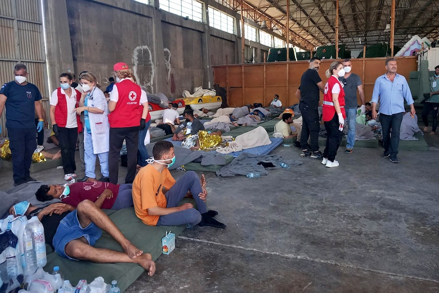 Survivors of a shipwreck rest at a warehouse at the port in Greece. 
