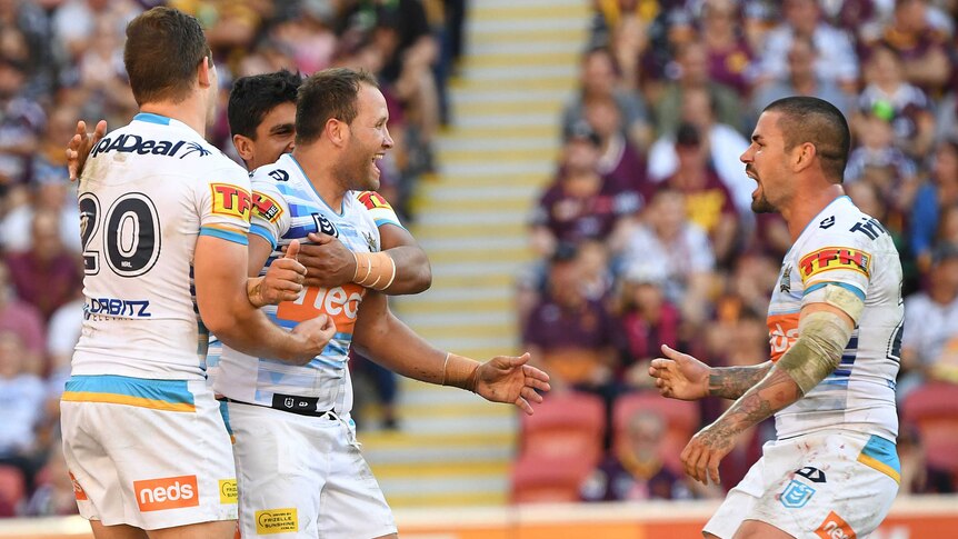 Tyrone Roberts is held by two Titans teammates as they celebrate his try against the Broncos.