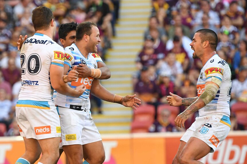 Tyrone Roberts is held by two Titans teammates as they celebrate his try against the Broncos.
