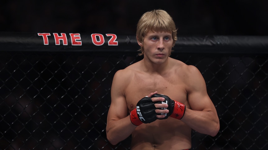 An MMA fighter puts his gloves together as he looks across the octagon before a UFC bout.