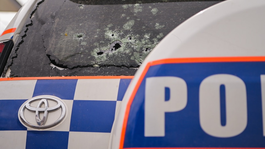 Bullet holes in the back windscreen of a police vehicle.