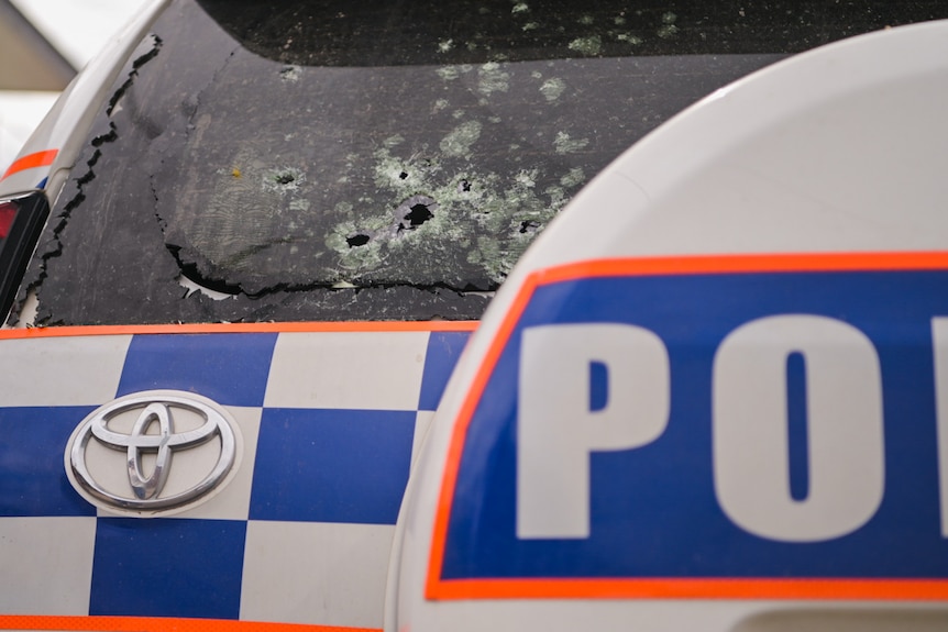 Bullet holes in the back windscreen of a police vehicle.