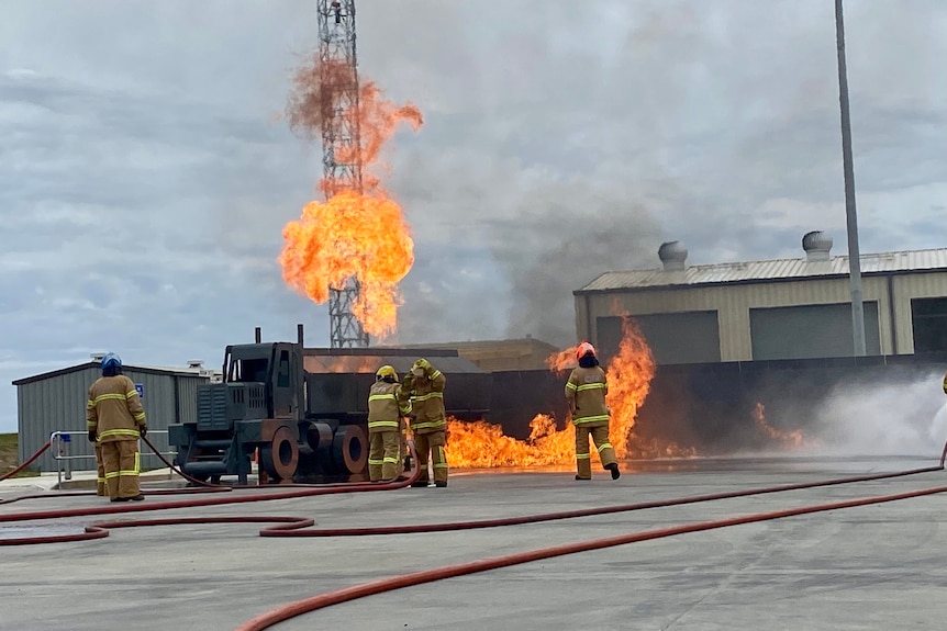 a group of CFA firefighters put out a fire in a tanker truck during a simulation. 