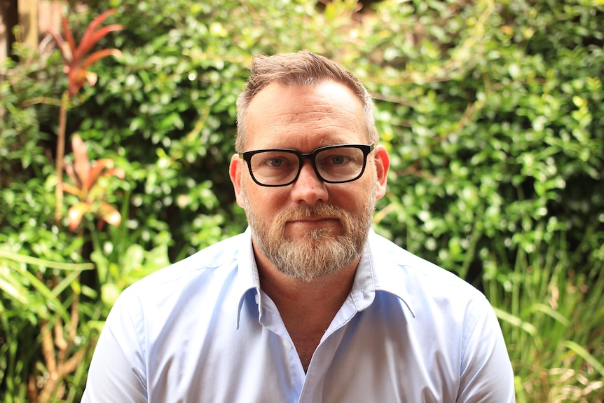 A man with glasses in the green grass.