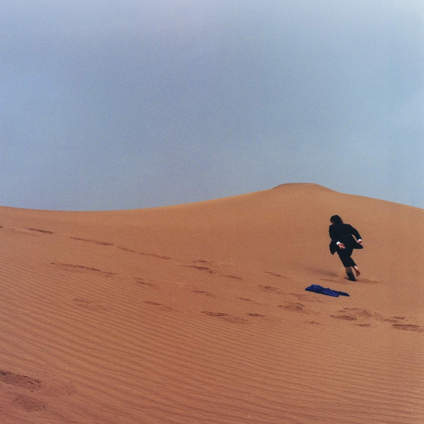 Front cover to Nick Murphy's second studio album, 'Run Fast Sleep Naked'. Photograph of Murphy in a suit running up a sand dune.