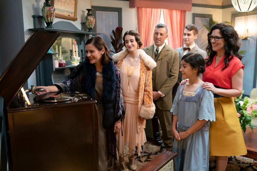 Crabb with family in period dress putting a record on old player.