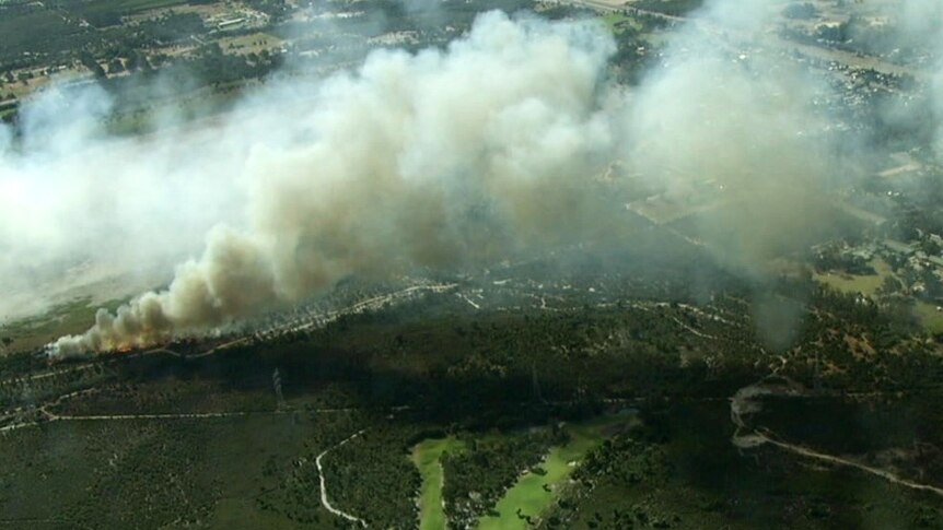 A bushfire burns through scrubland in a semi-rural area
