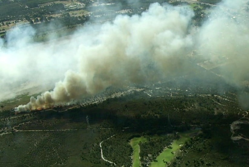 A bushfire burns through scrubland in a semi-rural area