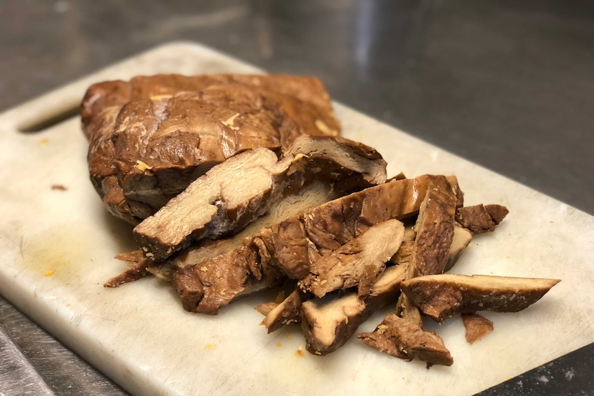 Strips of what appear to meat lie on a chopping board.