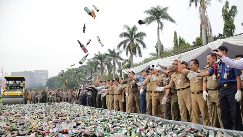 Indonesian officials throw bottles of alcohol in in the air as a steamroller destroys them in Jakarta.