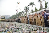 Indonesian officials throw bottles of alcohol in in the air as a steamroller destroys them in Jakarta.