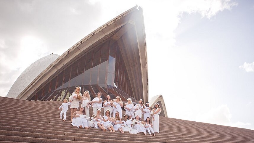 Women wearing white breastfeeding on the steps of the Sydney Opera House.