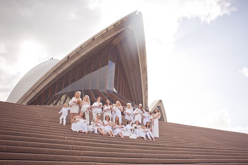 Women wearing white breastfeeding on the steps of the Sydney Opera House.