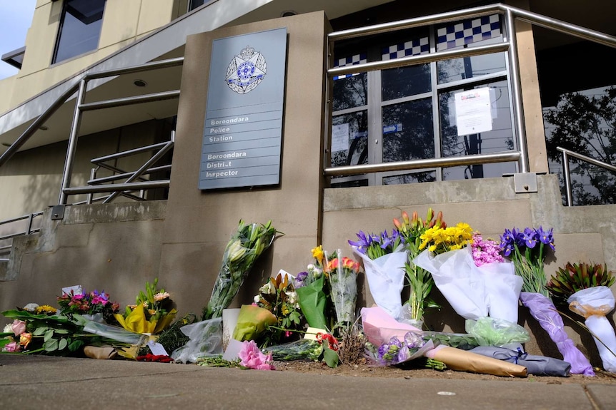 Bunches of flowers lay outside a police station.