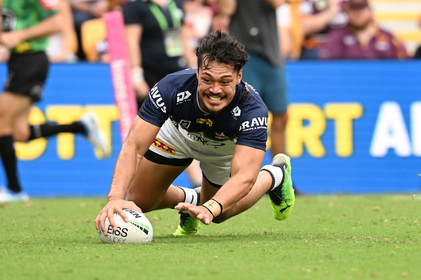 A North Queensland Cowboys NRL player dives to score a try.