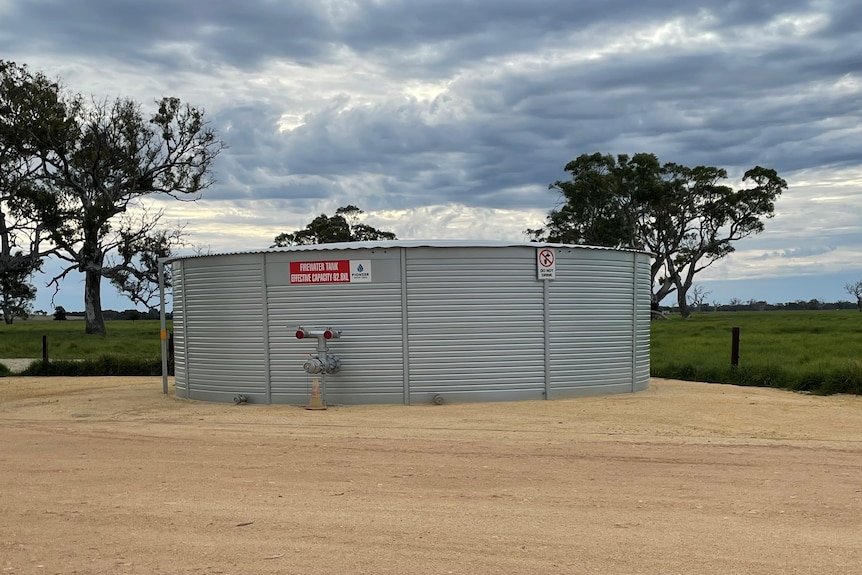 A large water tank with a grassy paddock behind