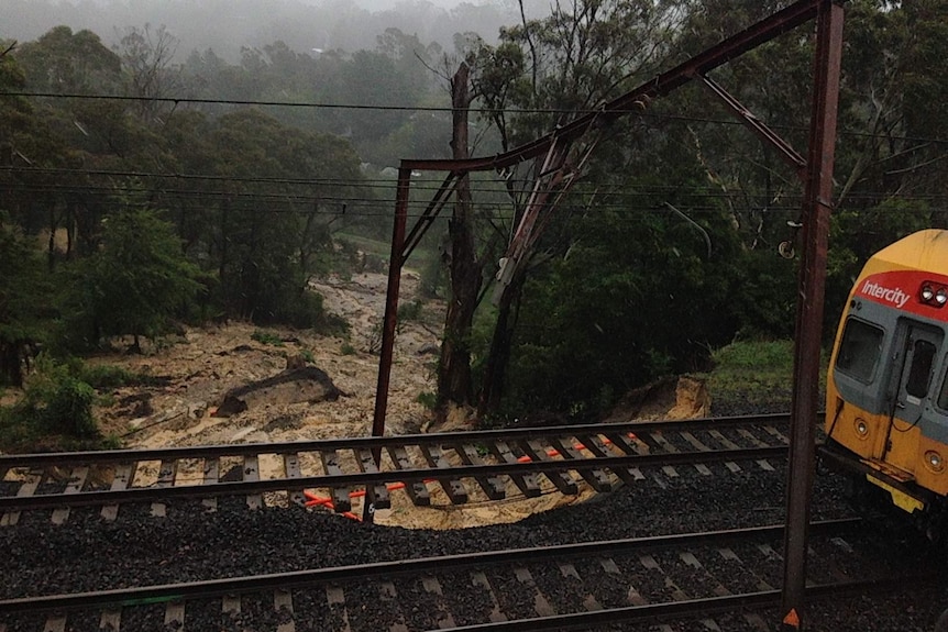 some train beams bent over broken ground beneath a train track