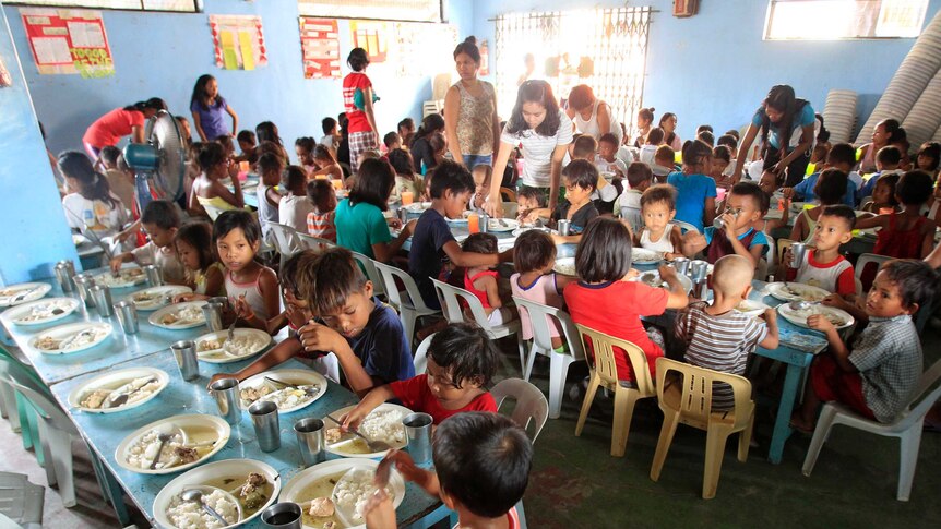 Children eat free meals during a feeding program at a slum area in Manila, Philippines