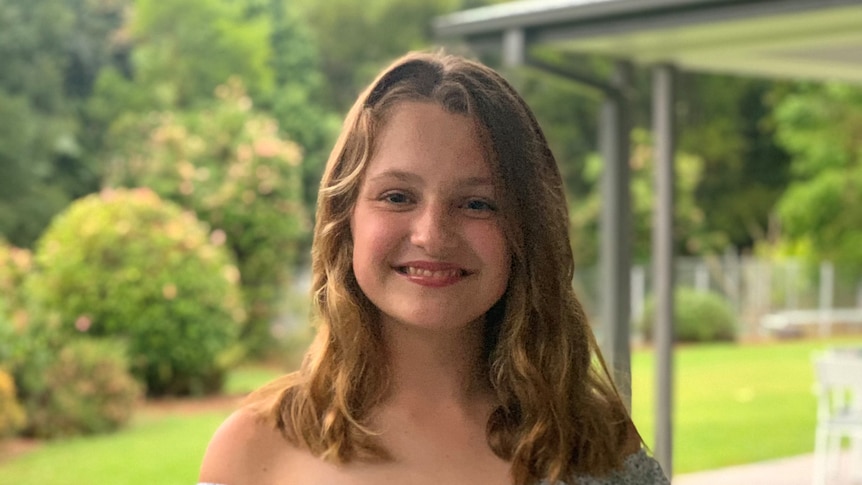 Headshot of 13 year old netballer Daisy Webber smiling. Daisy has long, dark blonde hair 