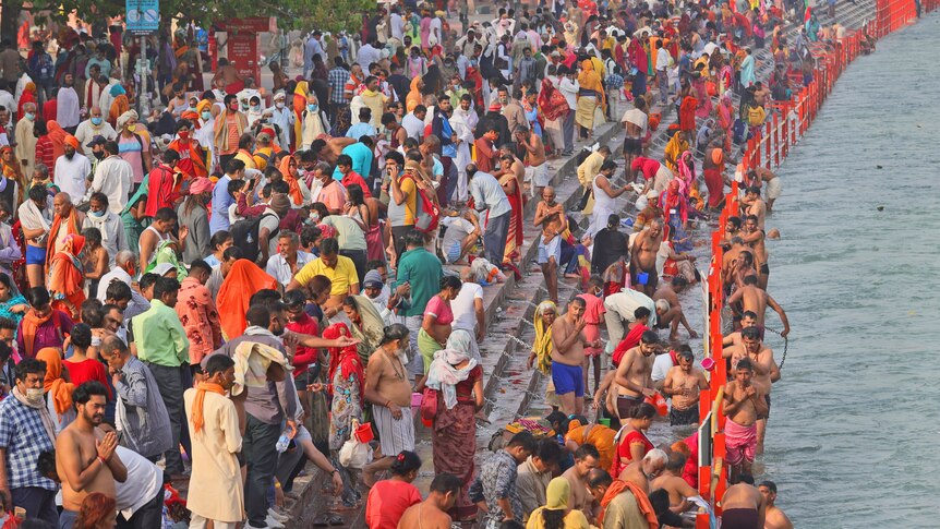 Crowds of people gather near the river bank