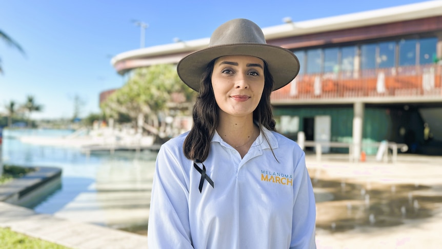 A woman with dark hair wearing a light colour Akubra hat and long sleeved white sun safe shirt.
