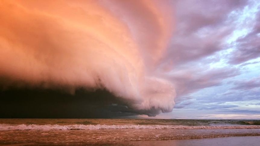 A huge, low-lying cloud looms over the water, turning the sky purple.