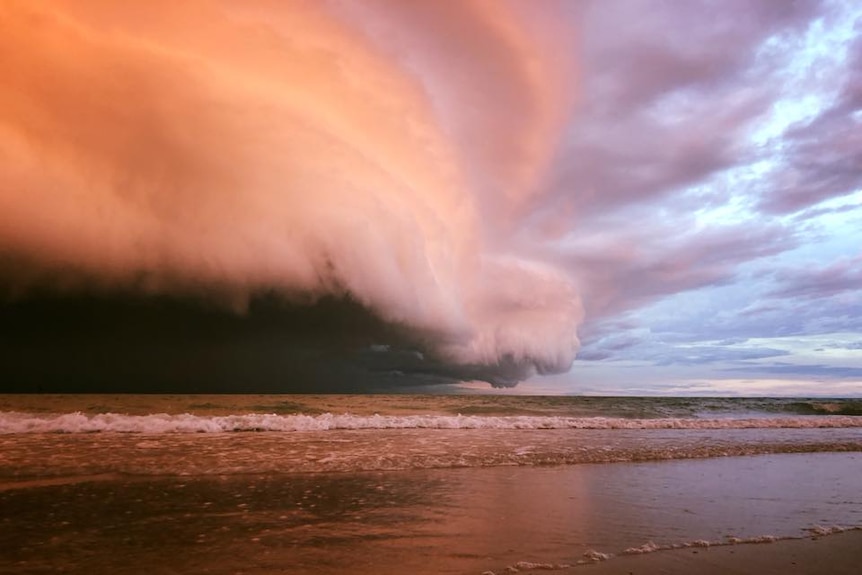 A huge, low-lying cloud looms over the water, turning the sky purple.