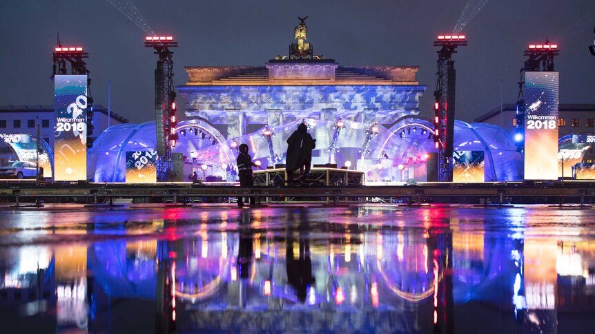 The illuminated Brandenburg Gate reflects in a puddle during a rehearsal prior to the New Year's Eve party
