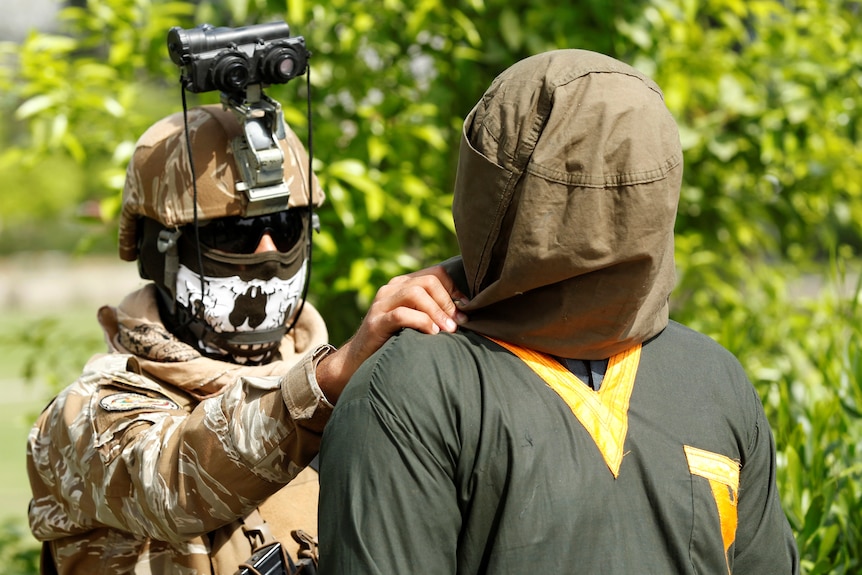 An Afghan soldier escorts a captured Taliban militant to a media presentation earlier this year.