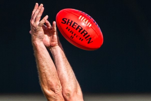 Unidentified AFL players' arms contesting for the ball in the air.