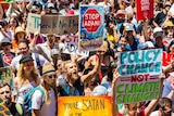 crowds holding anti-Adani and climate change signs chanting
