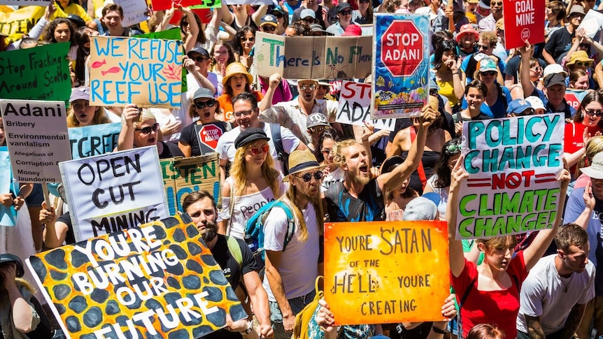 Crowds holding anti-Adani and climate change signs and chanting.