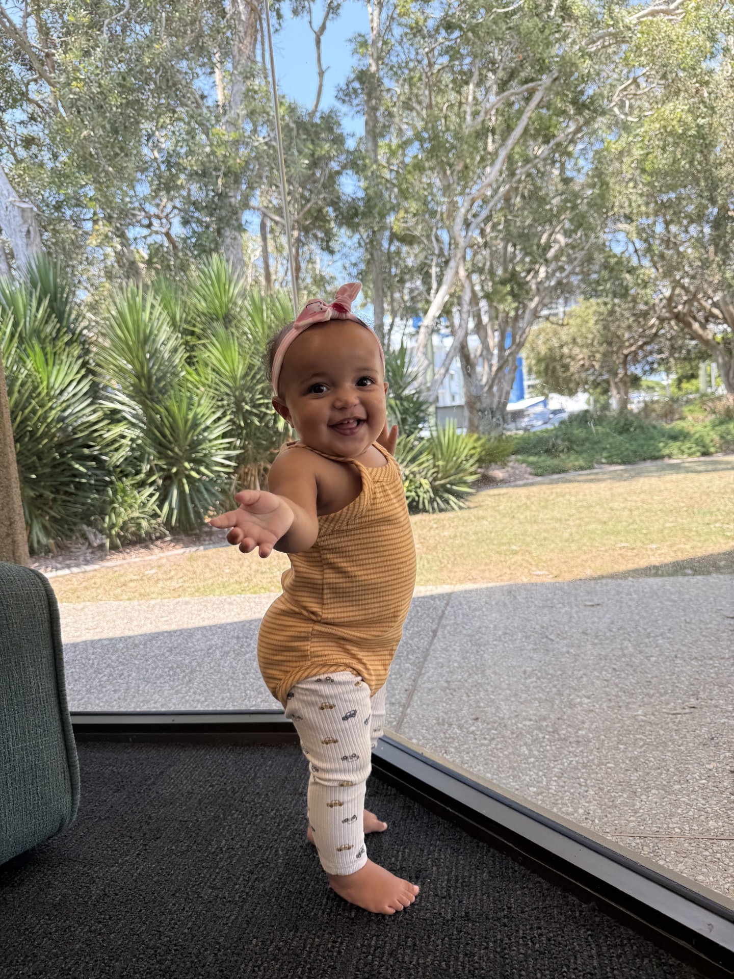Una niña muy joven posa de pie y sonriendo para la cámara.