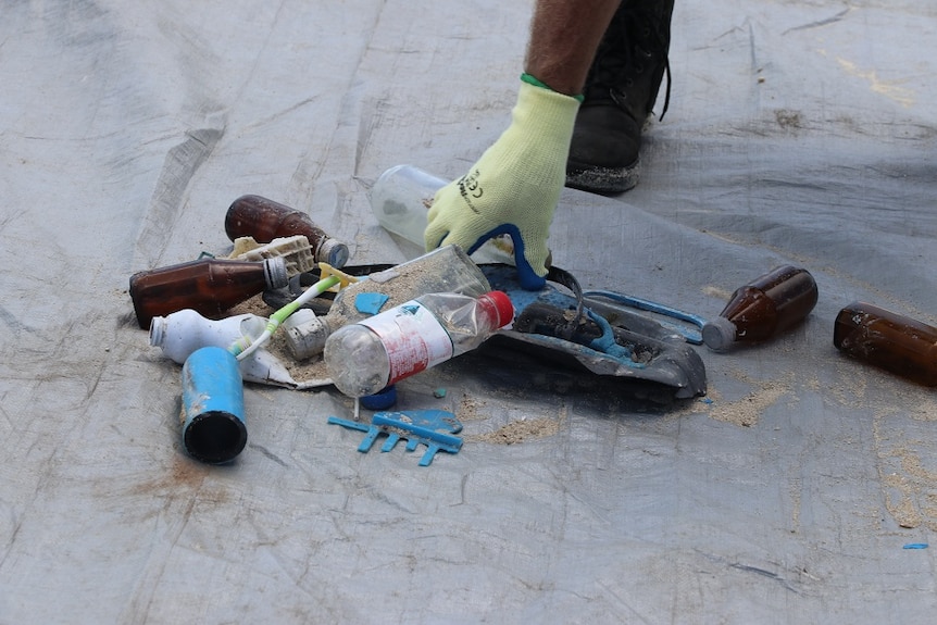 Piles of plastic bottles sitting on a tarp on the sandy island.