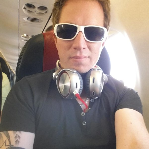 Jonathan William Parker wearing white sunglasses takes a selfie while sitting on a plane.