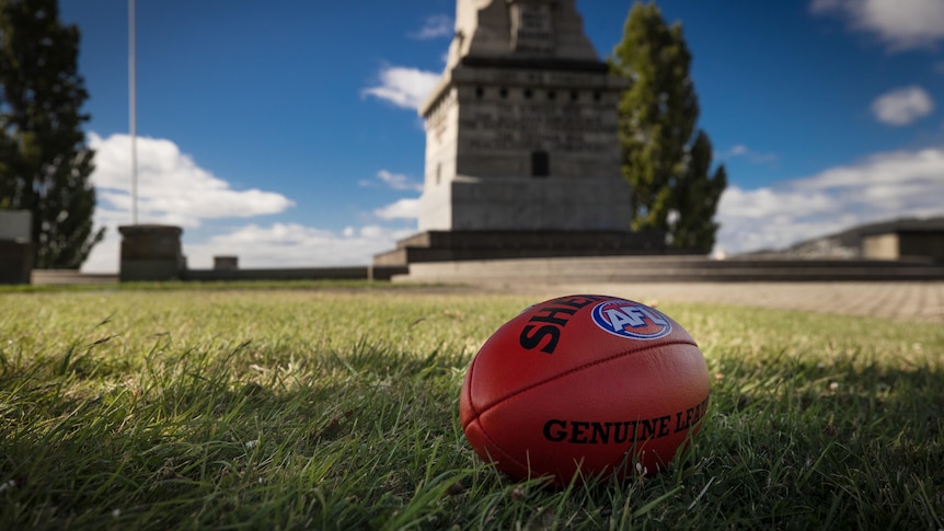 A red football sits on the grass next to Hobart Cenotaph.