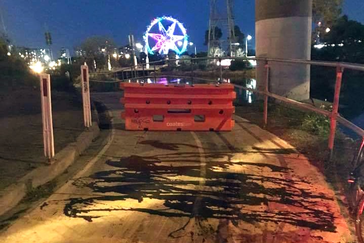 A safety barrier blocking Capital City Trail, with spilled oil in the foreground.