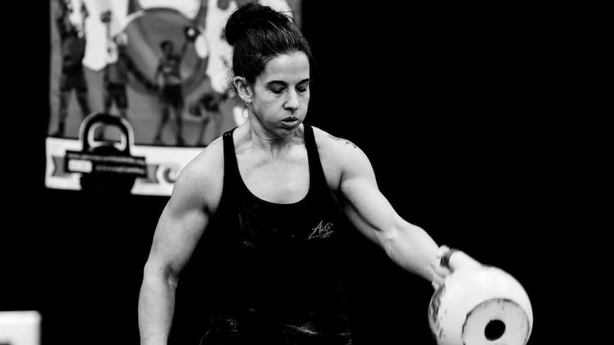 strong woman swinging a kettlebell in competition