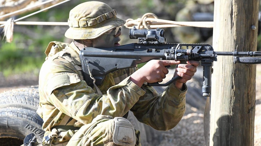 A man in army gear aims a gun.
