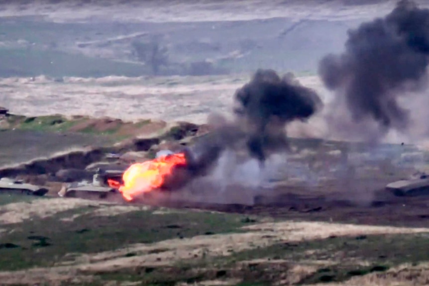 A still from footage shows blurry tank being engulfed in fire and black smoke.