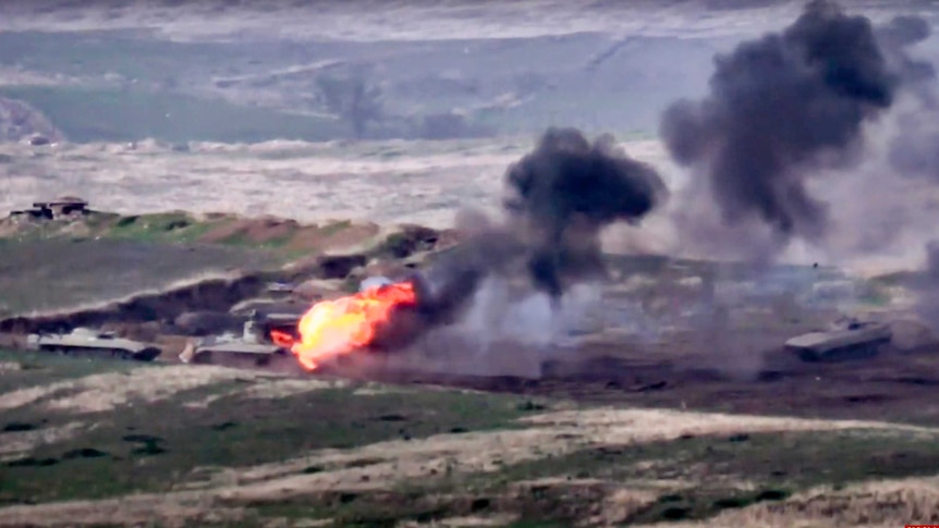 A still from footage shows blurry tank being engulfed in fire and black smoke.