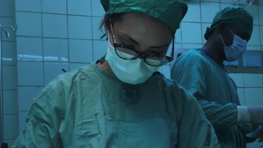 Yumiko Kadota wears surgical scrubs and mask during surgery on a patient.