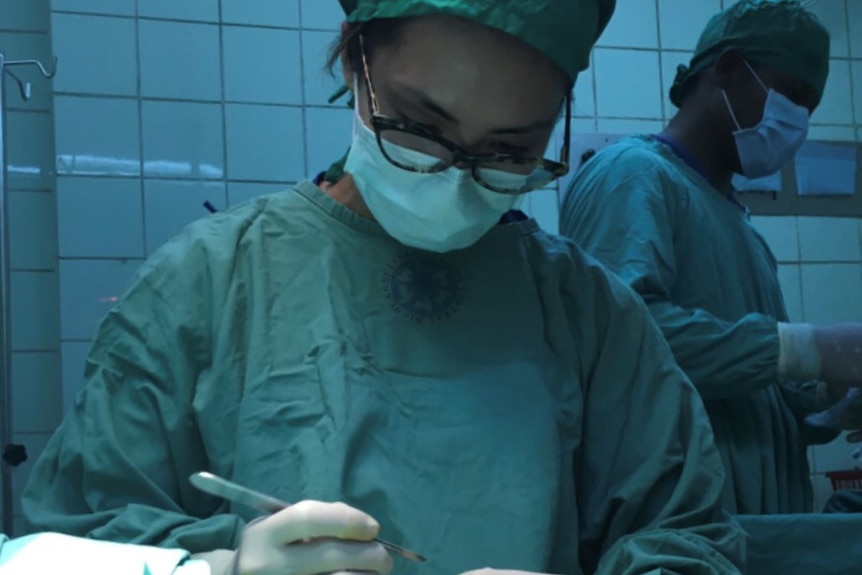 Yumiko Kadota wears surgical scrubs and mask during surgery on a patient.