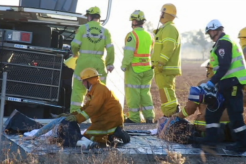 A CFA officer comforts an injured woman on the ground at the scene of a mini-bus crash.