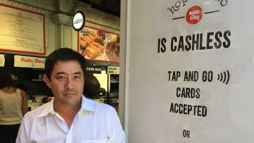 Marcus Chang in front of Spice Alley's cashless sign